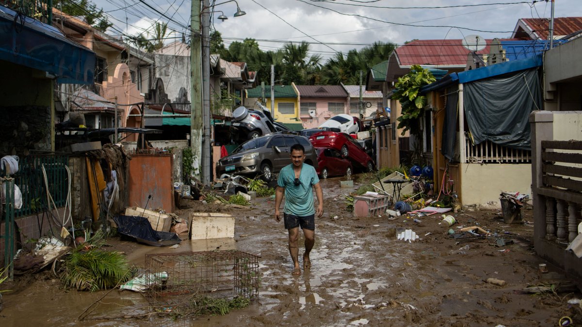 A man walks along a muddy street where cars piled up after being swept away in floods brought by Typhoon Kalmaegi pile up at a subdivision in Bacayan, Cebu City, Philippines, Nov. 5, 2025. (Reuters Photo)