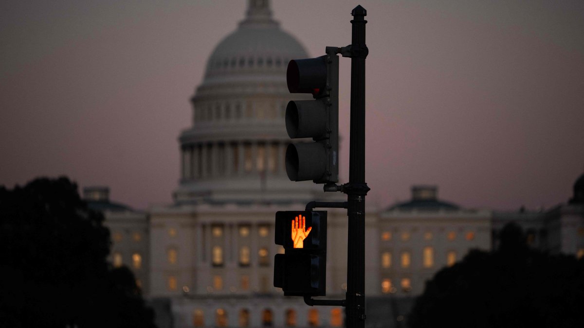 A crosswalk signal of a traffic light flashes backdropped by the U.S. Capitol in Washington, D.C., U.S., Oct. 1, 2025 (AFP Photo)