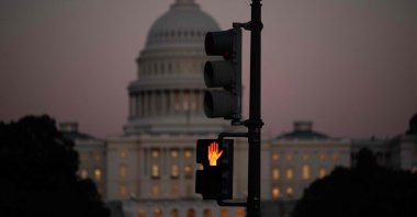 A crosswalk signal of a traffic light flashes backdropped by the U.S. Capitol in Washington, D.C., U.S., Oct. 1, 2025 (AFP Photo)