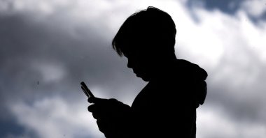 A 14-year-old boy poses at his home as he looks at social media on his mobile phone, Gosford, Australia, Oct. 24, 2025. (AFP Photo)