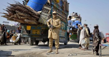 A Taliban security personnel stands guard as deported Afghan refugees from Pakistan arrive at the zero-point border crossing between Afghanistan and Pakistan, Kandahar province, Afghanistan, Oct. 27, 2025. (AFP Photo)