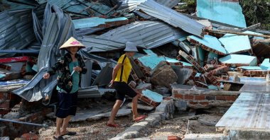 Residents walk over the debris of a structure destroyed in high winds in Nhon Hai fishing village near Quy Nhon in the aftermath of Typhoon Kalmaegi, Gia Lai province, Vietnam, Nov. 7, 2025. (AFP Photo)