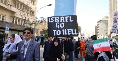 A woman holds a banner during a rally outside the former U.S. embassy as Iranians mark the 46th anniversary of the start of the Iran hostage crisis, in Tehran, Iran, Nov. 4, 2025. (AFP Photo)