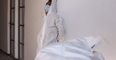 An employee of the Nasser Medical Complex rests near a body after it was released by Israel, Khan Yunis, southern Gaza Strip, Palestine, Oct. 31, 2025. (AFP Photo)