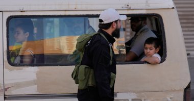 A Syrian government security man checks a minibus at a checkpoint in the southern Damascus suburb of Jaramana, Syria, Oct. 3, 2025. (AP Photo)