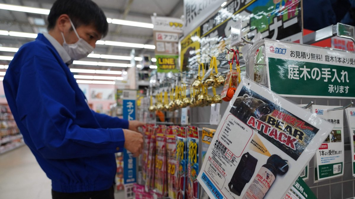 A staff member sorts bells next to an advertisement for bear spray at a store in Hanamaki, Iwate prefecture, Japan, Oct. 24, 2025. (AFP Photo)