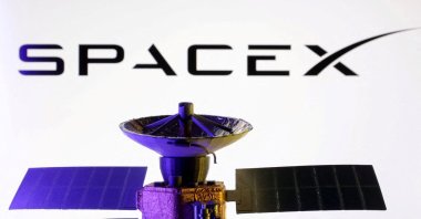 The SpaceX logo and miniature satellite model are seen in this illustration created March 10, 2025. (Reuters Photo)