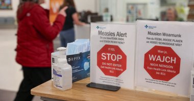 A woman passes by healthy awareness posters related to the measles outbreak during a public health awareness campaign, at the Taber Health Centre, in the largely Mennonite community of Taber, Alberta, Canada, Oct. 27, 2025. (Reuters Photo)