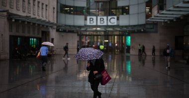 People shelter from the rain outside the entrance to the BBC in London, United Kingdom, Nov. 10, 2025. (AFP Photo)