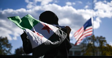 A man holds a Syrian flag across the street from the White House after Syrian President Ahmed al-Sharaa met with U.S. President Donald Trump at White House in Washington, D.C., U.S., Nov. 10, 2025. (AFP Photo)