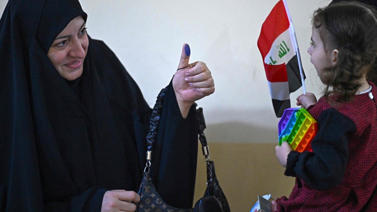 An Iraqi voter shows her ink-marked thumb to her daughter at a polling station in the southern city of Basra, Iraq, Nov. 11, 2025. (AFP Photo)