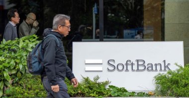 Pedestrians walk past signage outside the building where the SoftBank Group headquarters is located, Tokyo, Japan, Nov. 11, 2025. (AFP Photo)