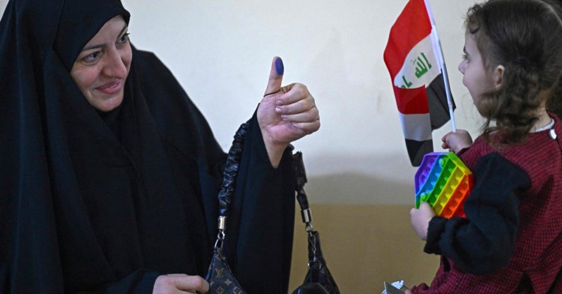 An Iraqi voter shows her ink-marked thumb to her daughter at a polling station in the southern city of Basra, Iraq, Nov. 11, 2025. (AFP Photo)