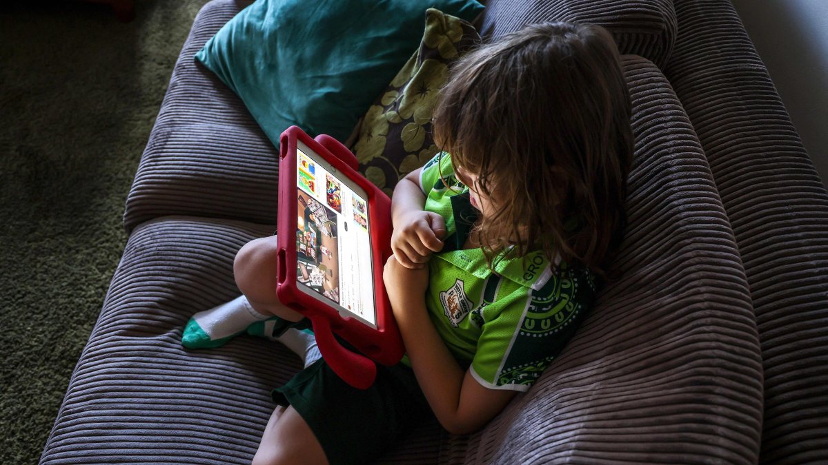 Six-year-old Enrique Navarro sits on a couch with his iPad watching a show on YouTube at his home in western Sydney, Australia, Oct. 30, 2025. (AFP Photo)