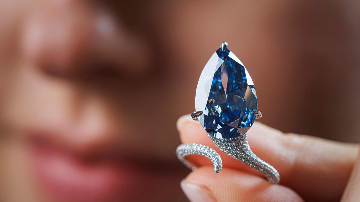 A staff member shows a 9.51-carat vivid blue diamond, known as "The Mellon Blue," during its presentation at Christie’s auction house, Geneva, Switzerland, Nov. 7, 2025. (AFP Photo)