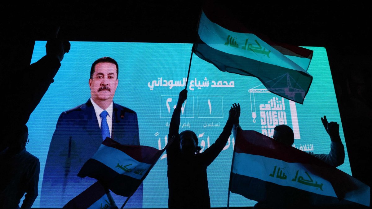 Supporters of incumbent Iraqi Prime Minister Mohammed Shia al-Sudani wave national flags in front of a screen displaying his portrait as they celebrate following the announcement of preliminary election results in Baghdad, Iraq, Nov. 12, 2025. (AFP Photo)