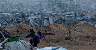 Palestinian children hold a piece of wood with the rubble of destroyed buildings in the background, in Jabalia, northern Gaza Strip, Palestine, Nov. 6, 2025. (Reuters Photo)