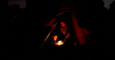 Displaced Palestinian Hanan al-Joujou sits with her child at the entrance of their tent, during a power cut, in Nuseirat, central Gaza Strip, Oct. 31, 2025. (Reuters Photo)