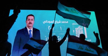 Supporters of incumbent Iraqi Prime Minister Mohammed Shia al-Sudani wave national flags in front of a screen displaying his portrait as they celebrate following the announcement of preliminary election results in Baghdad, Iraq, Nov. 12, 2025. (AFP Photo)