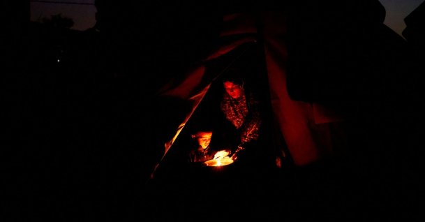 Displaced Palestinian Hanan al-Joujou sits with her child at the entrance of their tent, during a power cut, in Nuseirat, central Gaza Strip, Oct. 31, 2025. (Reuters Photo)