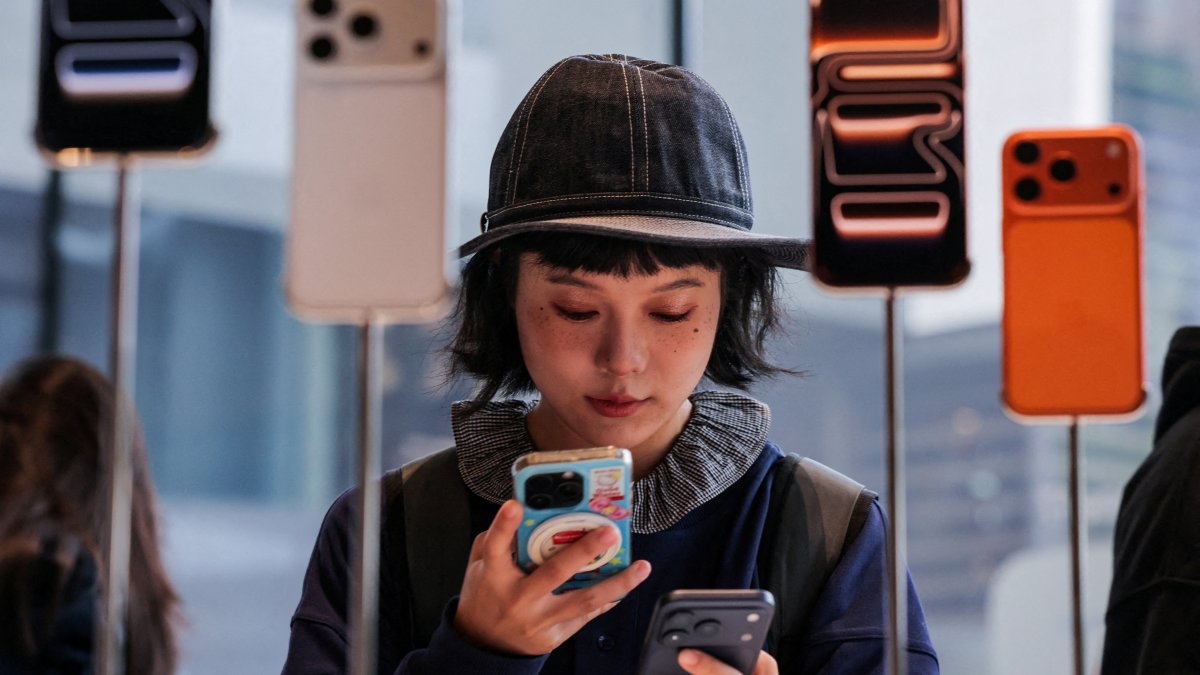 A woman uses her smartphone inside the Apple store as the new iPhone 17 series smartphones go on sale in Beijing, China, Sept. 19, 2025. (Reuters Photo)