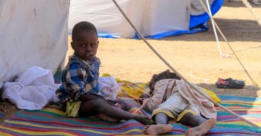 Children from el-Fasher rest outside their tent at a camp for displaced Sudanese people in the northern town of al-Dabba, Sudan, Nov. 13, 2025. (AFP Photo)