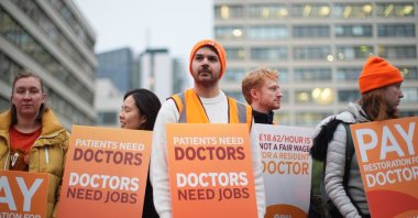 NHS resident doctors hold placards outside St. Thomas&#039; Hospital as thousands strike over pay, London, U.K., Nov. 14, 2025. (AP Photo)