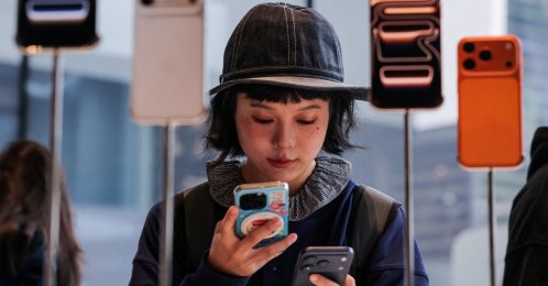 A woman uses her smartphone inside the Apple store as the new iPhone 17 series smartphones go on sale in Beijing, China, Sept. 19, 2025. (Reuters Photo)