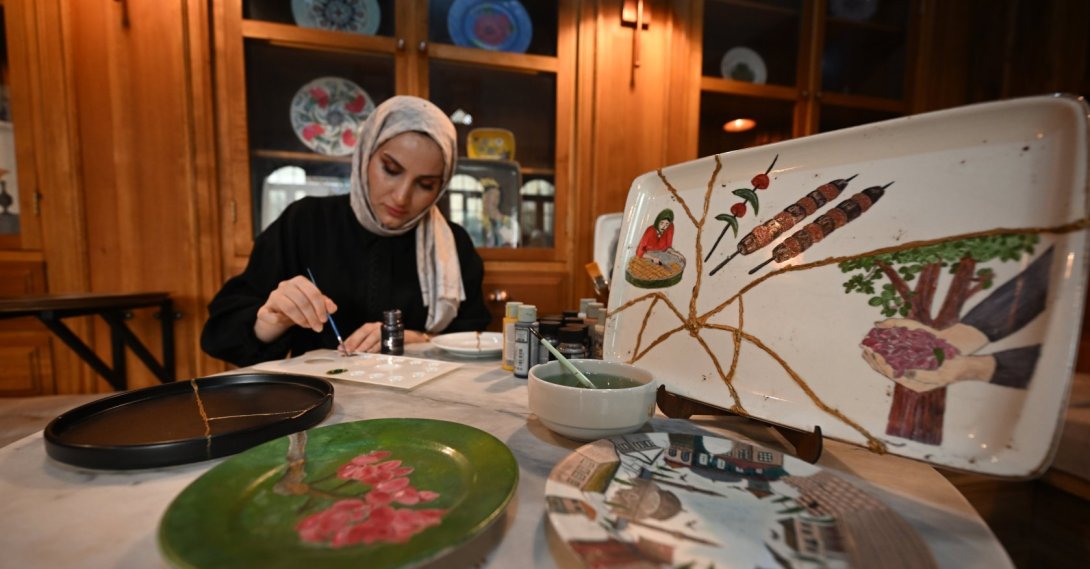 A woman paints a broken plate for recycling at Kayna Soap and Molasses Museum, Gaziantep, southeastern Türkiye, Nov. 11, 2025. (AA Photo)