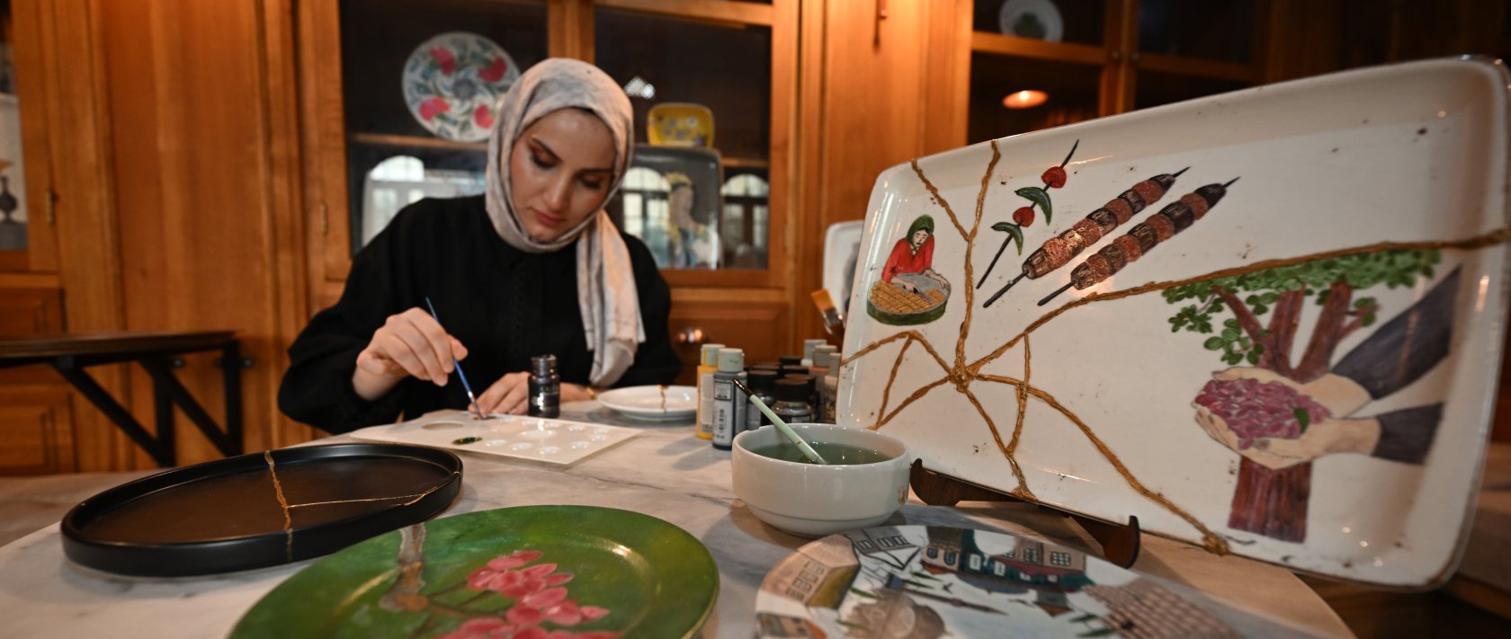 A woman paints a broken plate for recycling at Kayna Soap and Molasses Museum, Gaziantep, southeastern Türkiye, Nov. 11, 2025. (AA Photo)