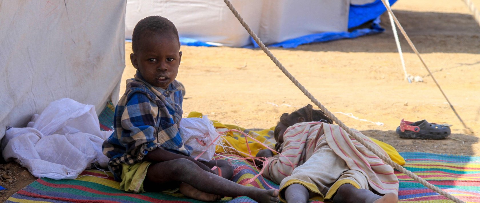 Children from el-Fasher rest outside their tent at a camp for displaced Sudanese people in the northern town of al-Dabba, Sudan, Nov. 13, 2025. (AFP Photo)