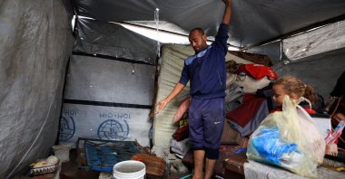 A Palestinian man removes water from the roof top of a tent on a rainy day, during a cease-fire between Israel and Hamas, in Gaza City, Nov. 14, 2025. (Reuters Photo)