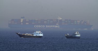 Two traditional dhows sail by a large container ship in the Strait of Hormuz, Iran, May 19, 2023. (AP Photo)