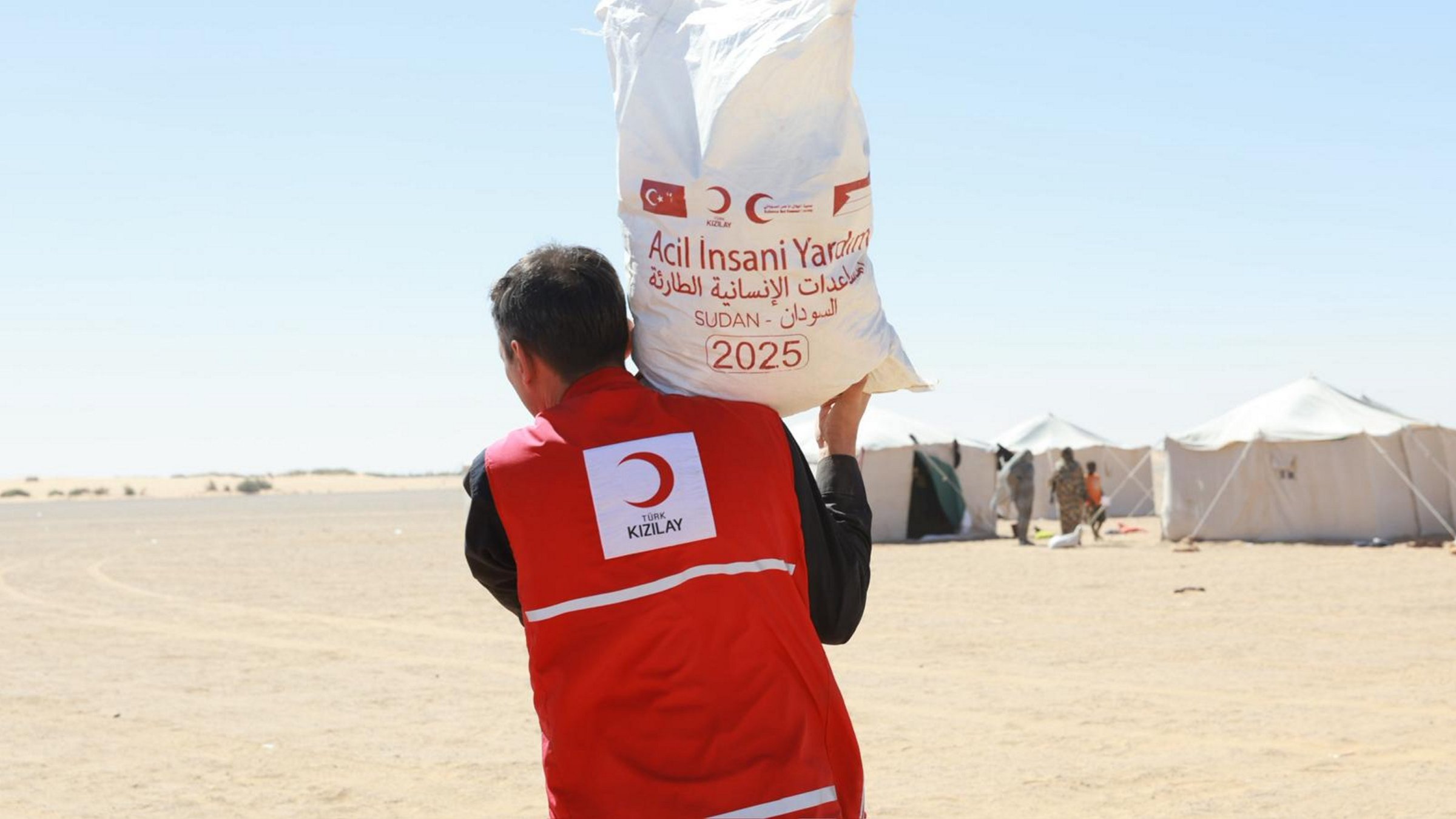 A Turkish Red Crescent (Kızılay) member carries essential food supplies to displaced families in ed-Debbe, northern Sudan, Nov. 15, 2025. (AA Photo)