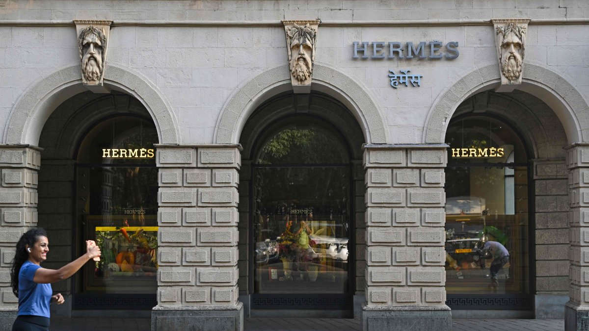 A woman makes a reel while running past the French luxury brand Hermes store, Mumbai, India, Nov. 14, 2025. (AFP Photo)