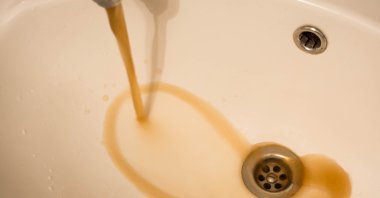 Dirty water streaming from a sink faucet due to maintenance works. (Shutterstock Photo)