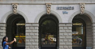 A woman makes a reel while running past the French luxury brand Hermes store, Mumbai, India, Nov. 14, 2025. (AFP Photo)