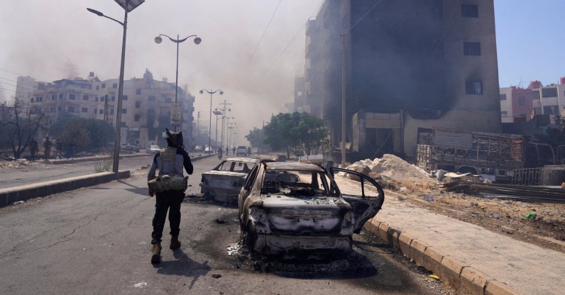 A Bedouin fighter walks with a weapon near damaged cars and buildings, following the Syrian presidency&#039;s announcement of a cease-fire after days of violence in Suwayda province triggered by clashes between Bedouin fighters and Druze factions, in Suwayda, Syria, July 19, 2025. (Reuters Photo)
