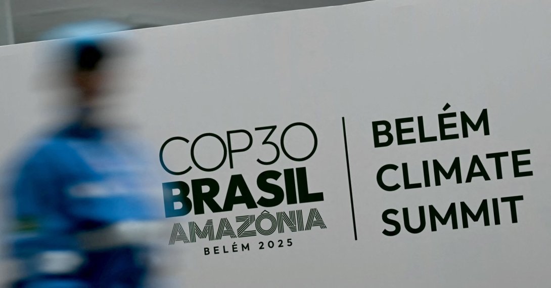 A worker walks past a banner with the COP30 UN Climate Change Conference logo inside the Hangar Convention and Exhibition Center in Belem, Para State, Brazil, Nov. 5, 2025. (AFP Photo)