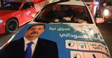 A man holds a flag of Iraq from a car with an election poster featuring current Prime Minister Mohammed Shia&#039; al-Sudani, as supporters of the Reconstruction and Development Coalition celebrate after preliminary election results were announced in Baghdad, Iraq, Nov. 12, 2025. (Reuters Photo)