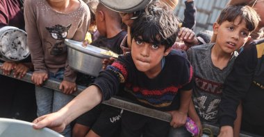 Young Palestinians wait with their containers to receive a portion of food in the Nuseirat refugee camp, in central Gaza Strip, Palestine, Nov. 10, 2025. (AFP Photo)