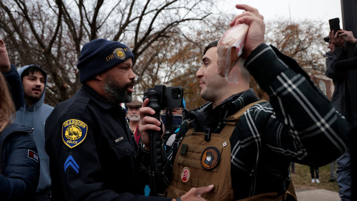 A Dearborn Police Officer confronts far-right activist Jake Lang, as he waves a package of bacon during a protest against Islam in Dearborn, Michigan, U.S. Nov. 18, 2025. (Reuters Photo)