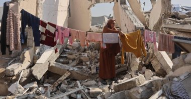 A Palestinian woman hangs clothes to dry amid the ruins of a building in Gaza City, Palestine, Nov. 18, 2025. (AFP Photo)
