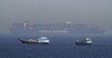 Two traditional dhows sail by a large container ship in the Strait of Hormuz, Iran, May 19, 2023. (AP Photo)