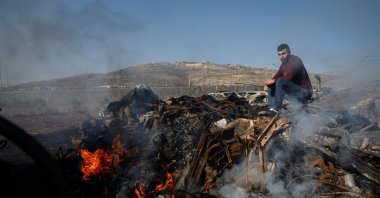 Palestinian man Yahya Dalal, 32, sits near cars burnt in an attack by Israeli settlers, in Huwara in the Israeli-occupied West Bank, Nov. 21, 2025. (Reuters Photo)
