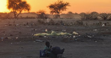 Sudanese brothers, refugees from el-Fasher, wash clothes at sunset outside the Tine transit camp, in eastern Chad, Nov. 22, 2025. (Reuters Photo)