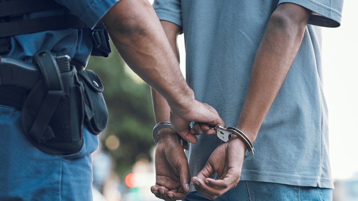 A police officer handcuffs a suspect during an arrest. (Shutterstock Photo)