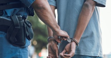 A police officer handcuffs a suspect during an arrest. (Shutterstock Photo)