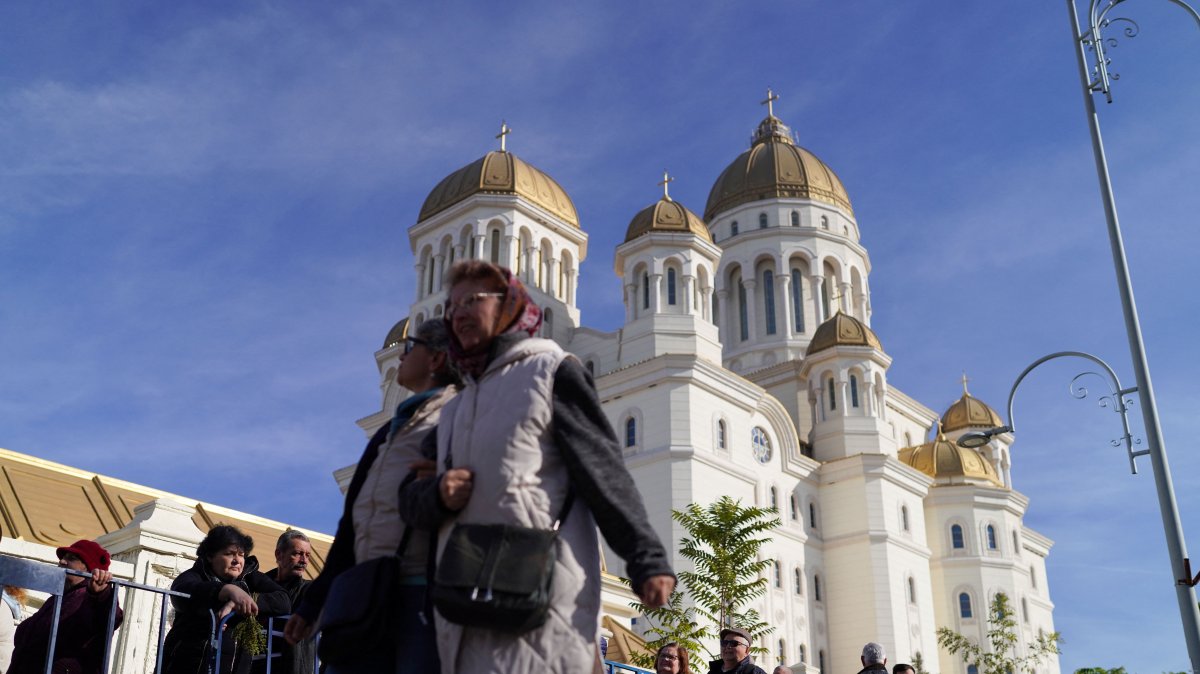 Two women walk past people waiting in line to visit the National Cathedral, Bucharest, Romania, Oct. 30, 2025. (Reuters Photo)