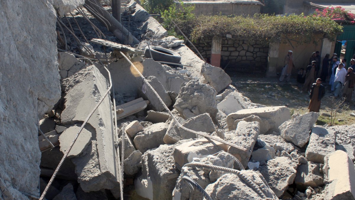 People stand in front of a damaged house that the Afghan Taliban government claims was damaged in Pakistani airstrikes, in Asadabad, Kunar province, Afghanistan, Nov. 25, 2025. (Reuters Photo)